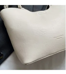 Gros plan détaillé du sac seau blanc cassé montrant la texture du cuir et les coutures nettes