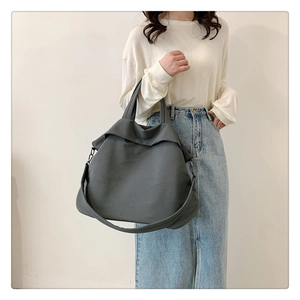 Détail d'un grand sac cabas gris en nylon avec boucles métalliques et bandoulière robuste