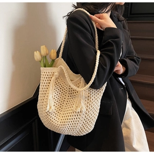 Détail du sac cabas au crochet avec texture ajourée et pompons tressés sur le côté