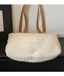 Detail of cream woven tote bag featuring sturdy texture and brown leather shoulder straps