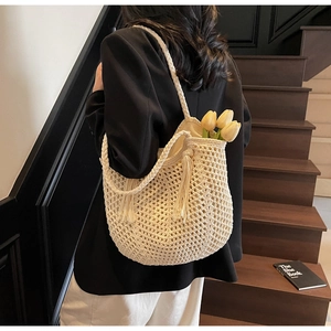 Détail d'un sac cabas crème tissé main avec motif en maille et pompons élégants