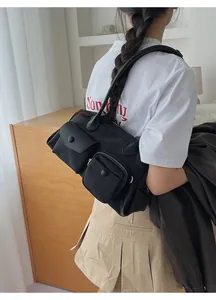 Detail view of a black multi-pocket shoulder bag with functional utility design style