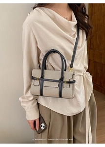 Vista dettagliata della borsa in tessuto beige con manici in pelle nera e accenti dorati