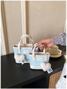 Detailed view of blue and white checkered tote bags with plush heart charms on a table