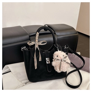 Détail du sac à main en cuir noir avec serrure en métal, foulard et lapin en peluche