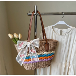 Detail of straw tote bag with lace bow and colorful accents on a floral display