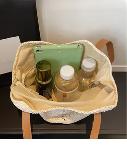 Detail of the large interior capacity showing items in the beige woven tote bag