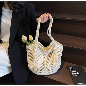 Détail d'un sac cabas tissé crème montrant la texture en maille et les pampilles élégantes