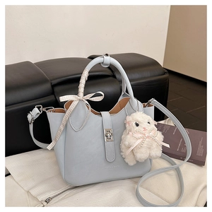 Détail du sac seau bleu clair avec un nœud en ruban et un joli pendentif mouton en peluche