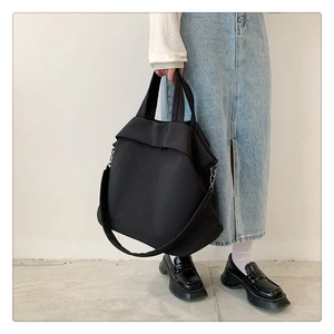 Détail du sac cabas en nylon noir avec une bandoulière large amovible et style épuré