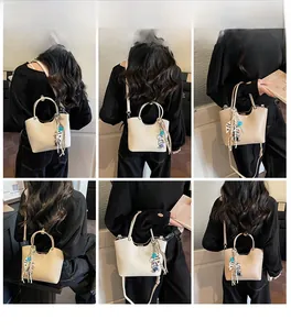 Sac seau beige en cuir avec pendentif ours présenté en plusieurs styles de portage