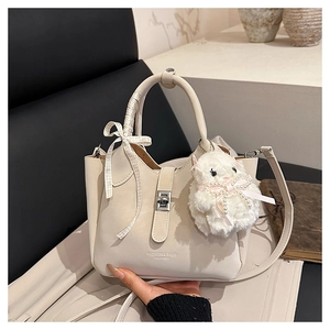 Détail du sac seau blanc cassé avec fermoir argenté, ruban à carreaux et breloque lapin