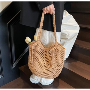 Détail du sac cabas en paille tissé à la main avec motifs ajourés et glands latéraux