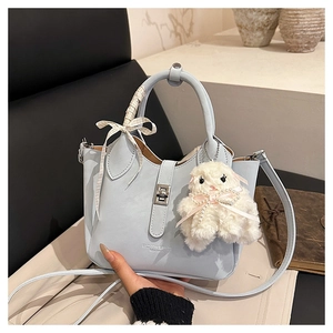 Vue détaillée du sac seau bleu clair avec fermoir rotatif argenté et charm lapin mignon