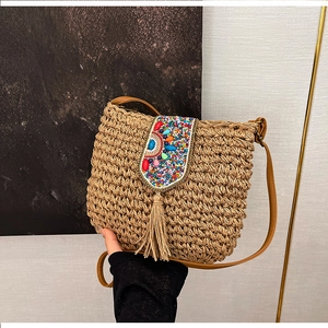 Close-up of handmade straw bag with colorful beads, tassels and leather strap