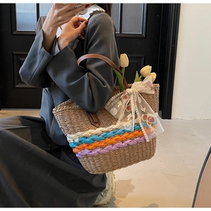 Detail of straw tote with colorful stripes, leather handles and a lace floral bow