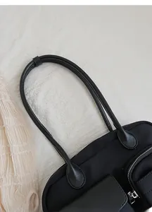 Detail of wide comfortable shoulder straps and silver zipper on black nylon tote bag
