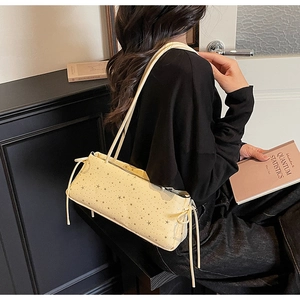 Detail of cream baguette bag featuring star patterns and side drawstring bow accents