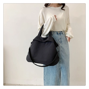 Grand cabas minimaliste en nylon noir porté par un mannequin pour montrer sa taille réelle