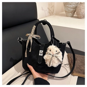 Détail du sac seau noir mat avec fermoir métallique, poignée ruban et breloque peluche