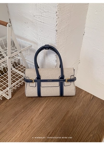 Dettaglio del corpo in tela beige e delle finiture in pelle blu scuro della borsa a mano