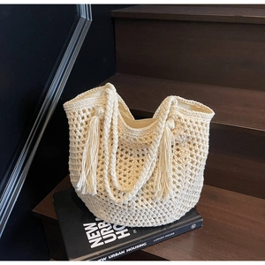 Détail du sac tissé crème avec maille géométrique, glands et doublure intérieure sur escalier