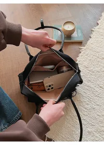 Top view of spacious interior of black shoulder bag with pockets and daily items
