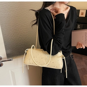 Detail of beige shoulder bag with star print and side drawstring on black outfit