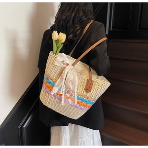 Detail of woven straw tote bag with colorful stripes, lace bow and floral embroidery