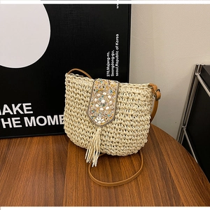 Detail of woven straw bag featuring ethnic beads, shell accents, and elegant fringe tassels