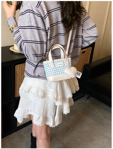 Detail view of mini plaid crossbody bag with bow patterns and heart plush keychain charm