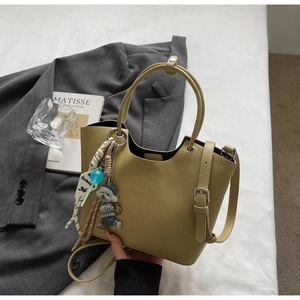 Détail du sac seau vert olive avec bandoulière réglable et breloque peluche mignonne