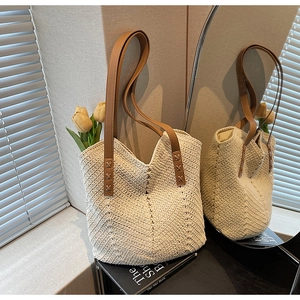 Detailed view of cream woven straw tote bag with reinforced brown faux leather handles