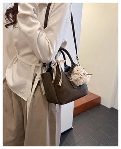 Détail d'un sac à main en cuir marron avec ruban à carreaux et breloque agneau