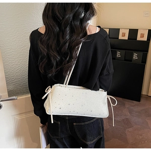 Detailed view of a white shoulder bag with silver star prints and side ribbon tassels