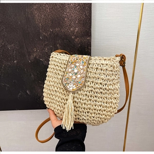 Detail of bohemian woven straw bag with shell bead embroidery and soft hanging tassels
