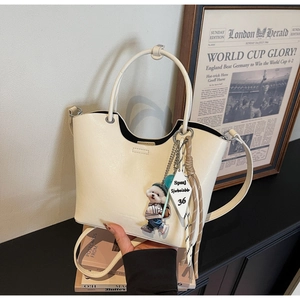 Détail d'un sac seau blanc crème avec poignée ronde et breloque chiot tricotée