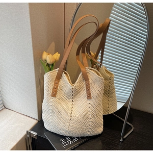 Detail of cream woven tote bag featuring V-shaped texture and brown leather straps