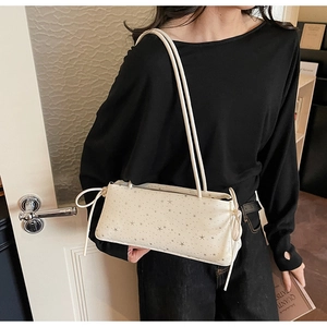 Lifestyle shot of cream baguette bag with star patterns and drawstring details