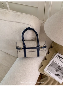 Dettaglio del tessuto beige intrecciato e pelle blu navy sulla borsa a mano firmata