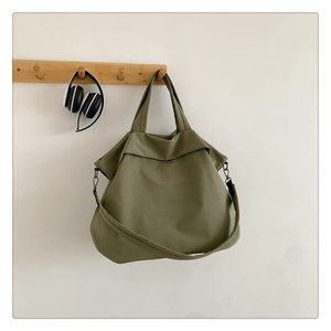 Gros plan d'un sac cabas en nylon vert olive suspendu à un crochet en bois avec boucles