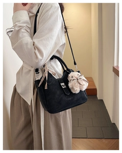 Détail du sac cabas noir mat avec ruban à carreaux jaunes et accessoire en peluche blanche