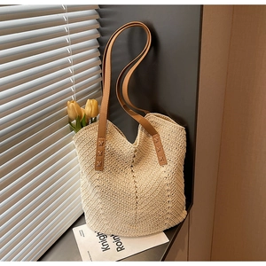 Detail of woven beach tote bag featuring V-pattern texture and brown leather handles