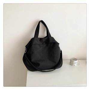 Détail d'un grand sac cabas en nylon noir avec doubles poignées et bandoulière réglable