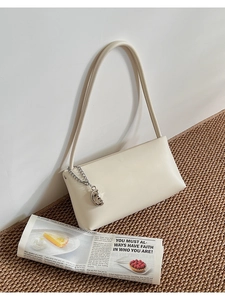Close-up of minimalist cream white baguette bag with matte leather and silver chain detail