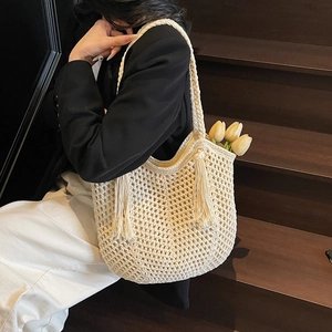 Sac fourre-tout tissé crème élégant avec glands à franges sur un modèle dans un escalier