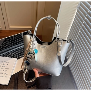 Détail du sac seau argenté avec pendentif chiot et sucette bleue sur un bureau moderne