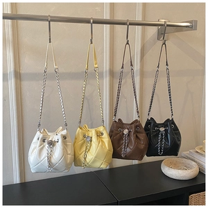 Quilted bucket bags in beige, yellow, brown, and black hanging with chain straps