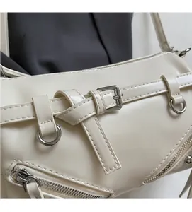 Detailed close-up of beige faux leather handbag with polished silver hardware and buckles