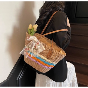 Detail of hand-woven straw tote with colorful patterns and white floral lace bow